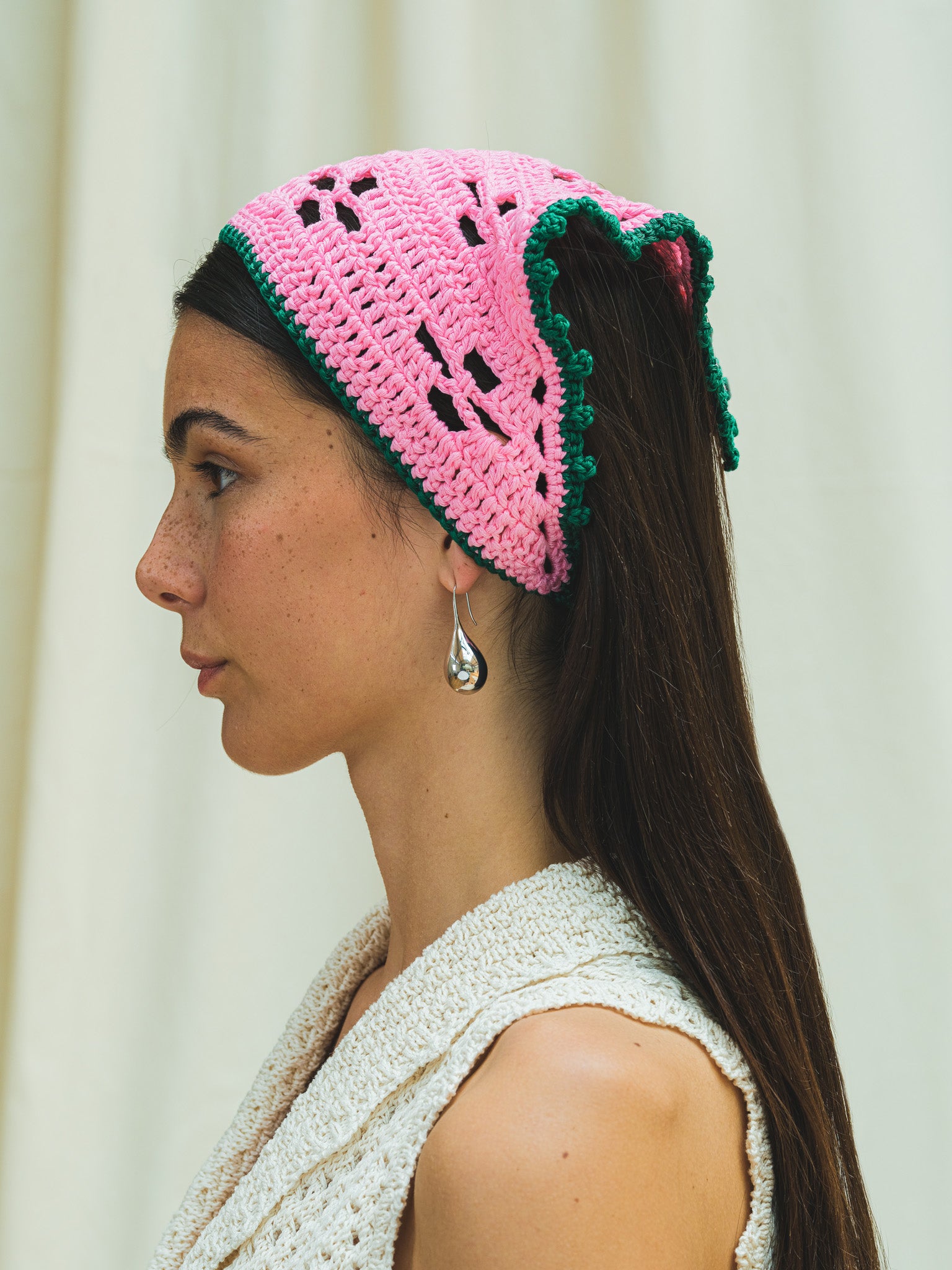 Side view of hand crocheted bandana in peony pink with emerald trim.