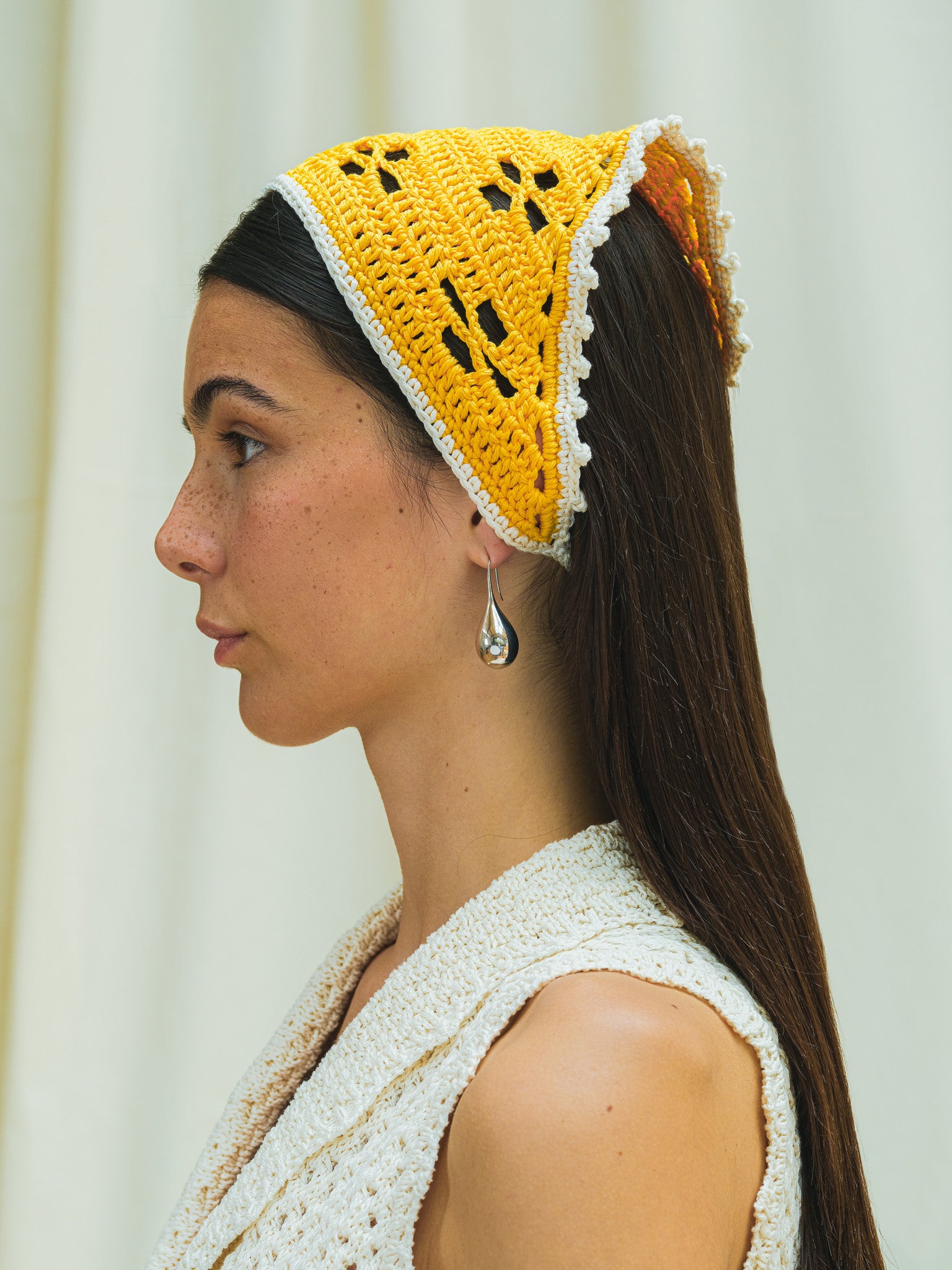 Side view of hand crocheted bandana in capri yellow and with linen white trim.