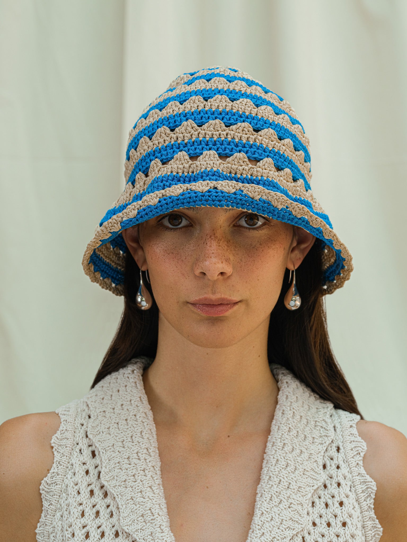 Front view of hand crocheted shell sun hat in almond and cerulean stripe