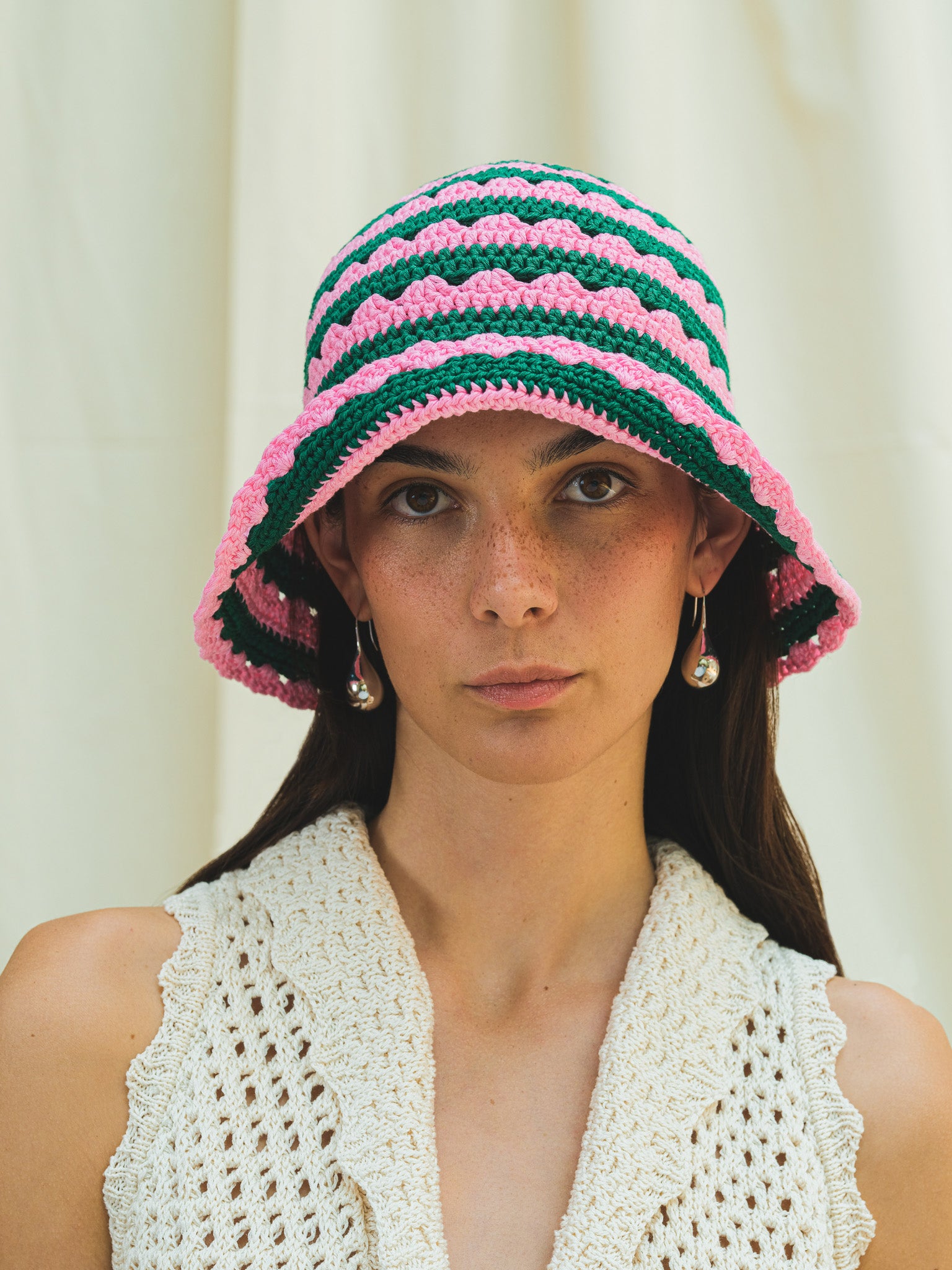Front view of hand crocheted shell sun hat in peony pink and dark emerald stripe