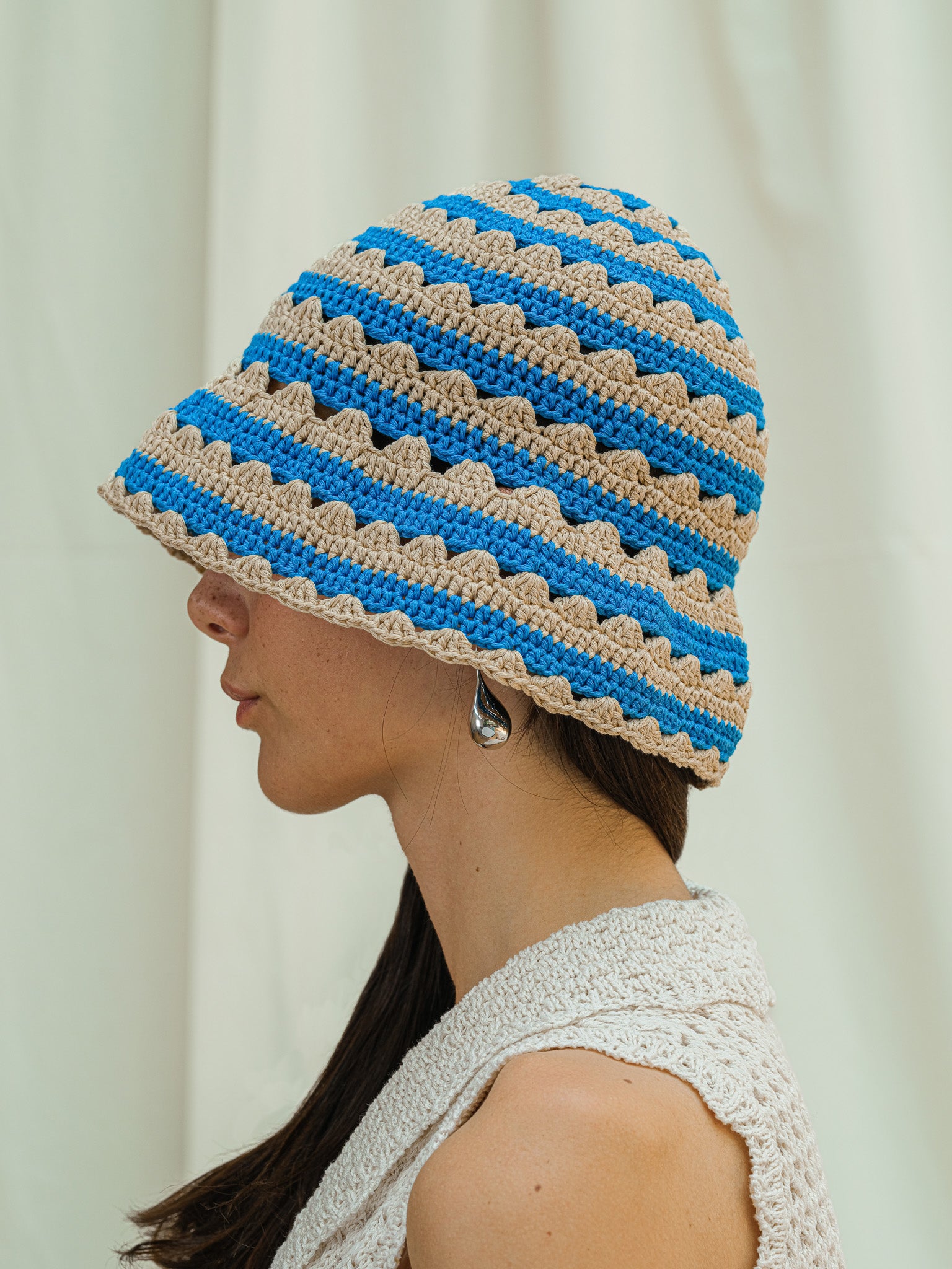 Side view of hand crocheted shell sun hat in almond and cerulean stripe