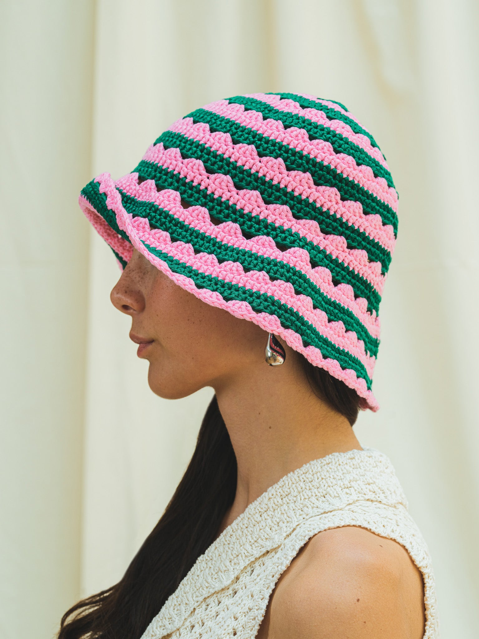 Side view of hand crocheted shell sun hat in peony pink and dark emerald stripe