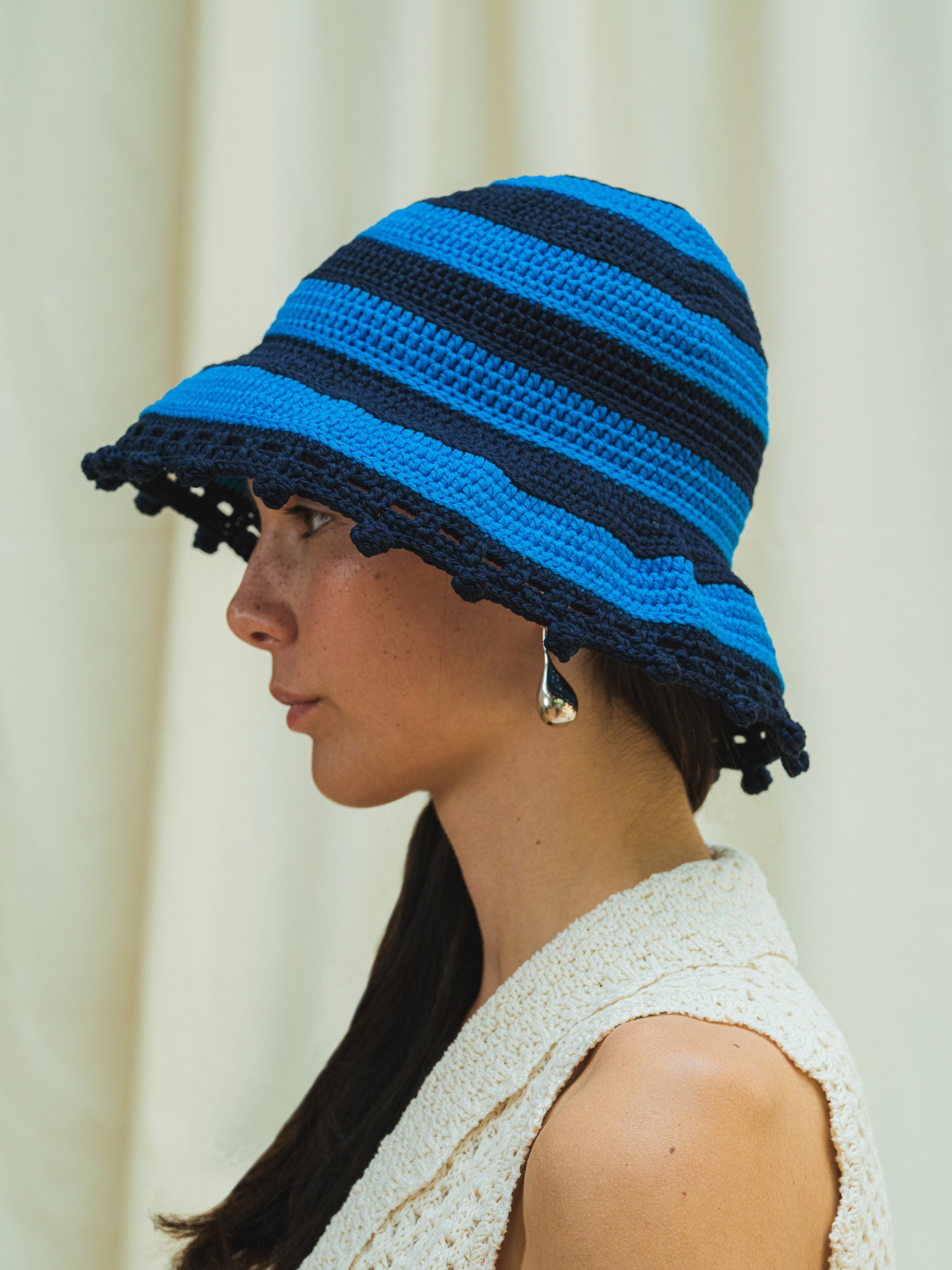 Side view of wide brim sun hat in cerulean and navy stripe with pom pom detail
