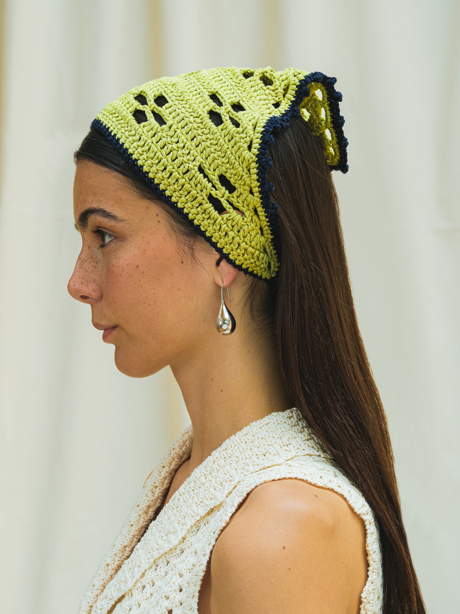 Side view of hand crocheted bandana in pistacchio with navy trim.
