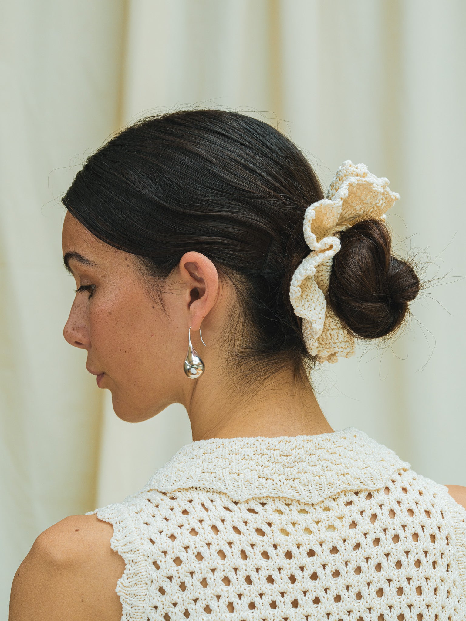Side view of hand crocheted scrunchie in linen white.
